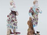 two figurines of a man and a woman standing on a rock