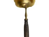 an antique brass spoon with a wooden handle on a white background