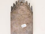 a small metal object on the wall with a sticker on it