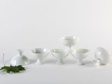 cinq vases blancs posés les uns à côté des autres sur une surface blanche