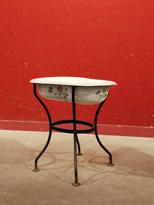 une petite table sur laquelle est posé un bol, devant un mur rouge