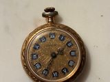 a gold pocket watch with roman numerals on it