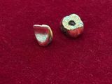 un gros plan sur une paire de perles métalliques posées sur une surface rouge