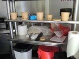 a metal shelf with pots and cups on it in a kitchen