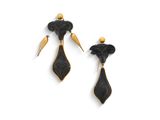 Les boucles d'oreilles noires et dorées sont disposées sur un fond blanc