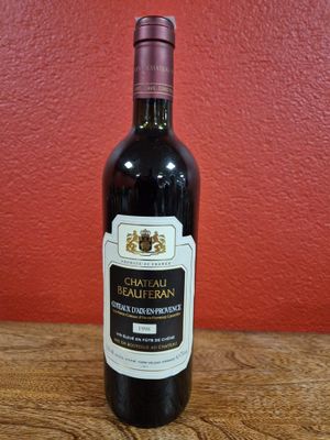 une bouteille de vin posée sur une table devant un mur rouge