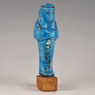 statue d'un homme vêtu d'une robe bleue, debout sur un bloc de bois