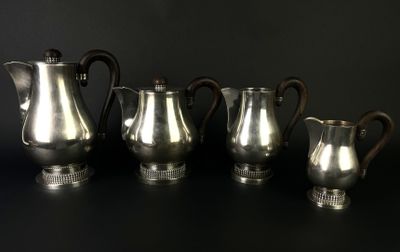 three silver coffee pots and two silver cups on a black surface