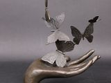 une sculpture représentant une main tenant un bouquet de papillons