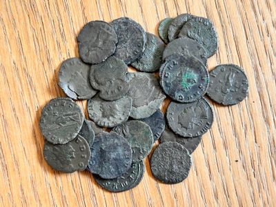 un tas de vieilles pièces romaines posées sur une table en bois
