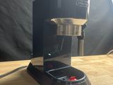 une photo d'une cafetière noire posée sur une table en bois