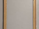 two gold framed mirrors on a wall next to a mirror