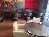 tables and chairs in a restaurant with a large painting on the wall
