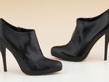 une paire de chaussures à talons hauts noires posées sur une surface blanche