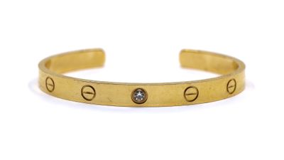 a close up of a gold bracelet with a diamond on it