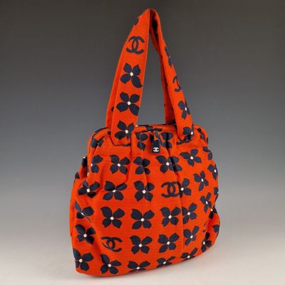 un sac à main orange orné de fleurs noires et blanches