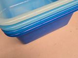 a blue plastic container sitting on a table next to a red chair