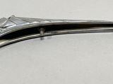 a silver metal hair clip on a white surface