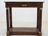une vieille table en bois avec un plateau en marbre posée sur un sol blanc