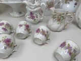 a lot of white and purple tea cups and saucers on a table