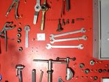 a red wall with a bunch of tools hanging on it
