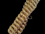 gros plan d'un bracelet en chaîne en or sur fond noir
