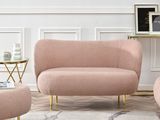 Le salon est équipé d'un canapé, d'un fauteuil et d'un pouf roses.