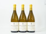 trois bouteilles de vin blanc posées les unes à côté des autres sur une table