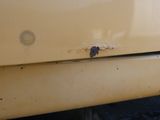 a close up of a yellow truck with rust on it ' s bumper