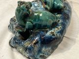 a ceramic sculpture of a cat and a dog laying on a rock