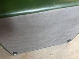 un banc vert posé sur un plancher en bois