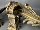 a pair of ornately carved wood brackets on a gray surface