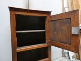 une armoire en bois dont la porte est ouverte, dans une pièce