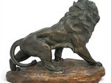 bronze statue of a lion on a rock on a white background