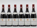 six bouteilles de vin sont alignées sur une surface blanche