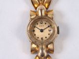 a gold clock with a bow on it on a white surface