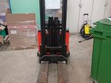 a fork lift truck in a garage with a green trash can