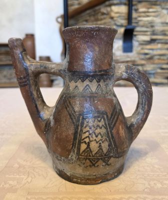 a brown vase sitting on a table with a stone wall in the background