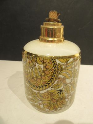a white and gold vase with a gold lid on a table