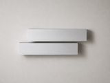 a close up of two white shelves on a wall