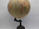 une petite statue représentant un homme debout au sommet d'un globe terrestre
