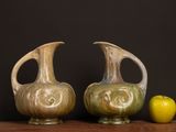 two vases sitting next to an apple on a table
