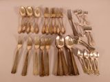 un grand nombre de cuillères et de fourchettes en argent disposées sur une table