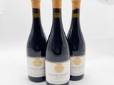 trois bouteilles de vin posées sur une table blanche