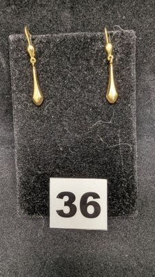 deux paires de boucles d'oreilles en or exposées dans une vitrine