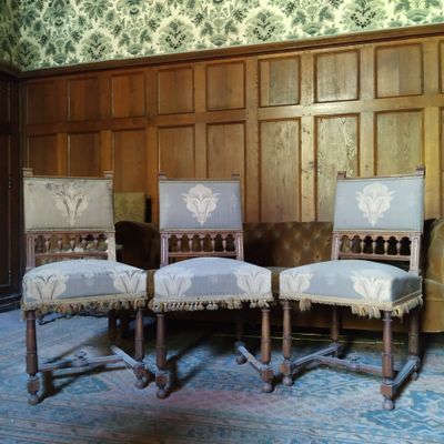 trois chaises dans une pièce dont les murs sont recouverts de boiseries