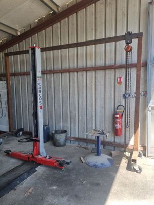 un garage avec un pont élévateur rouge au milieu du sol