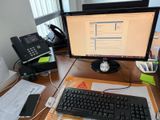 un bureau sur lequel se trouvent un ordinateur, un clavier, un téléphone et une imprimante