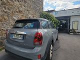 the car is parked in front of a building with a stone wall behind it