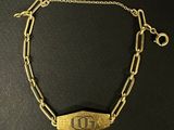 un gros plan sur un bracelet à chaîne en or orné de la lettre « d »